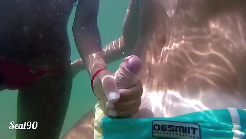 Amateur brunette in a beach enjoys a handjob under the water